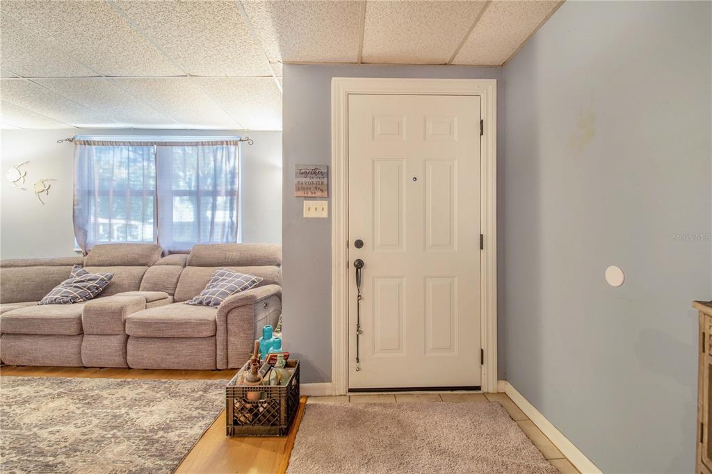 A living room features a gray sofa, a white front door, and a tiled entryway — 308 GRANADA ROAD, AUBURNDALE, FL