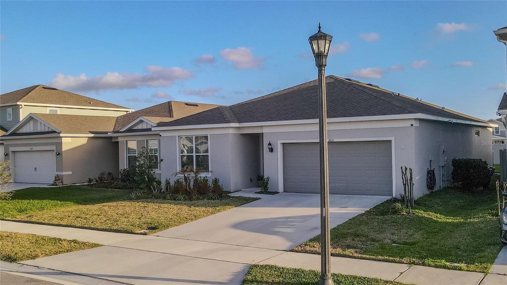 A single-story suburban house with a gray exterior, a two-car garage, and a streetlamp — 1821 GROVELINE ROAD, ST CLOUD, FL