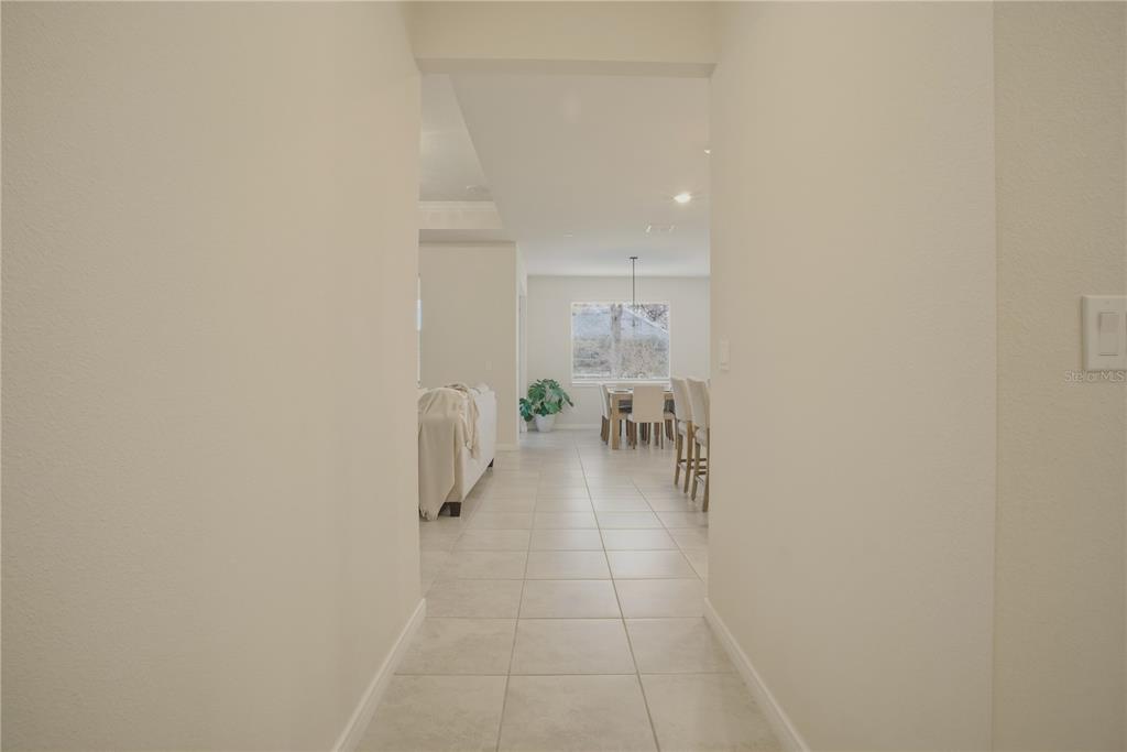 A view through a hallway into a dining area with tile flooring and a window — 1821 GROVELINE ROAD, ST CLOUD, FL