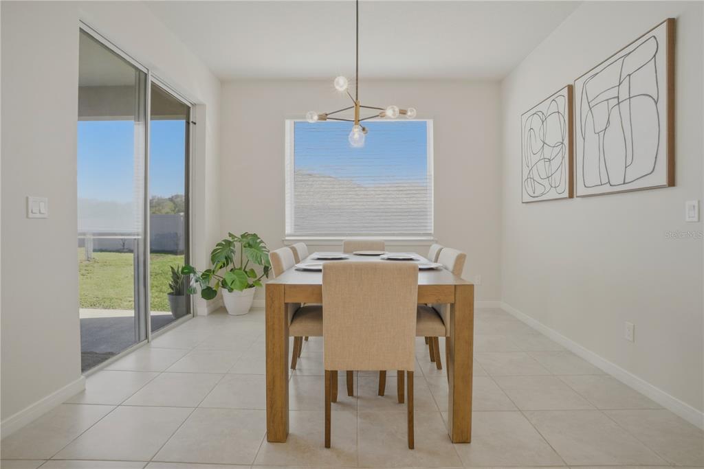 A dining room with a wooden table, six chairs, a chandelier, and a sliding glass door — 1821 GROVELINE ROAD, ST CLOUD, FL