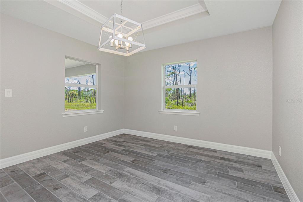 A room with gray walls, wood-look tile flooring, a tray ceiling, and a white chandelier — 6 BULK COURT, PLACIDA, FL