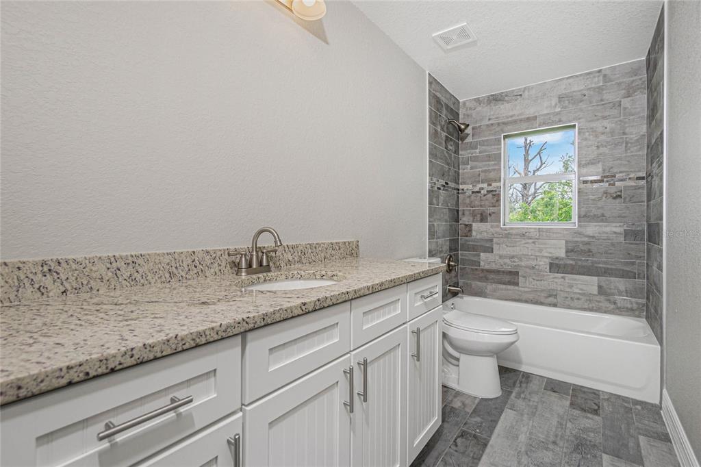 A bathroom features a granite vanity, white cabinets, and a tiled tub-shower combination — 6 BULK COURT, PLACIDA, FL