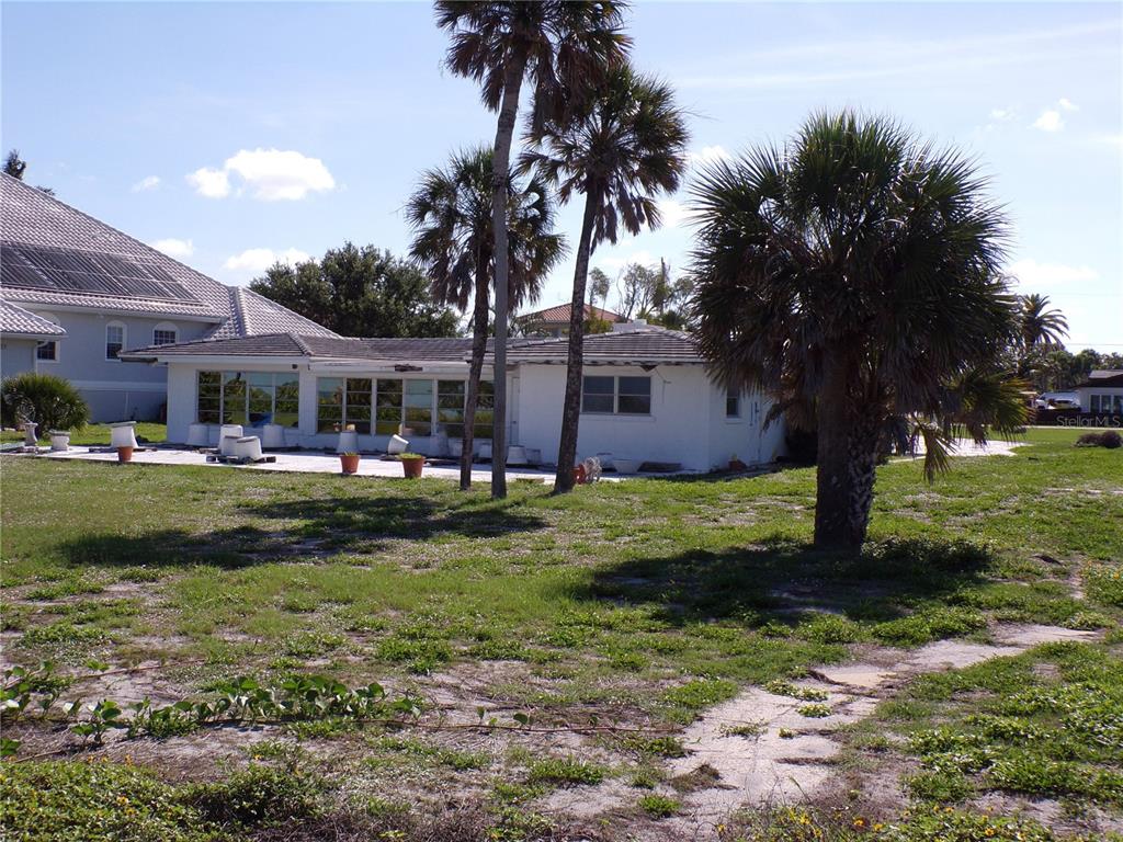 A white, single-story house with a flat roof and large windows sits on a grassy lot — 1124 SUNSET DRIVE, VENICE, FL