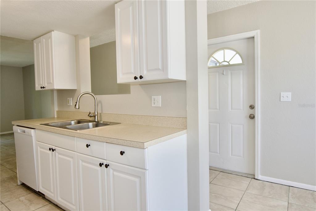 A kitchen features white cabinets, a light-colored countertop, a stainless steel sink, and tile flooring — 5310 26TH STREET W UNIT 2604, BRADENTON, FL