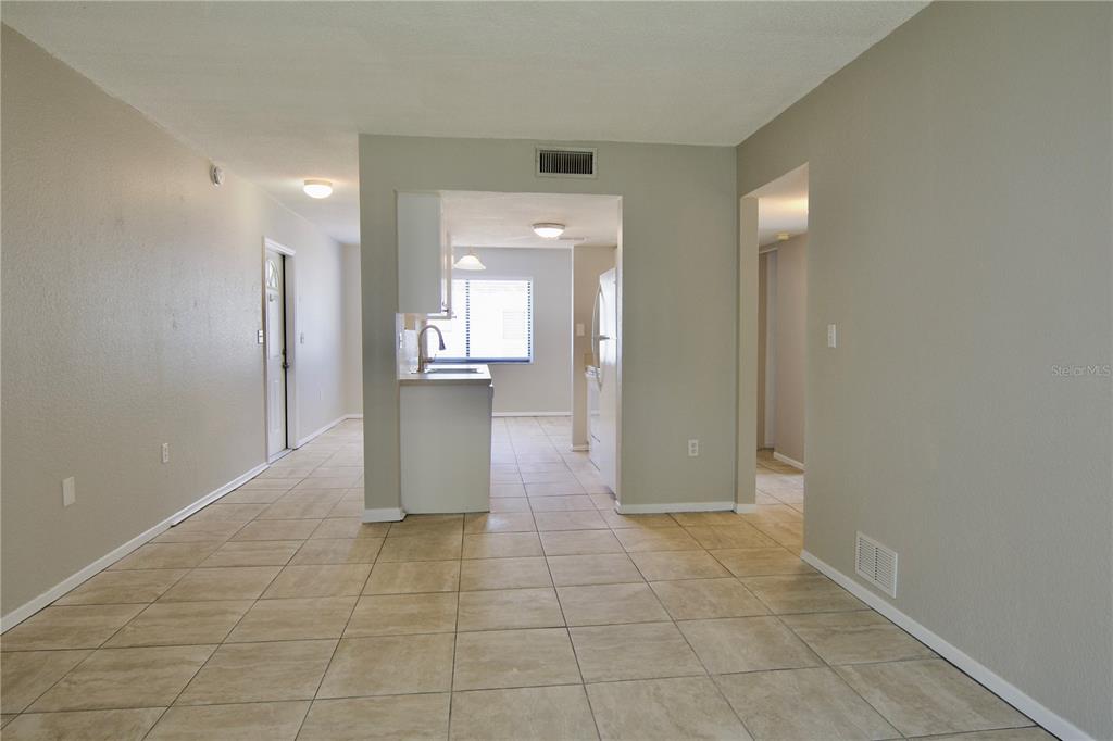 A tiled living area opens into a kitchen with white cabinets and a window — 5310 26TH STREET W UNIT 2604, BRADENTON, FL