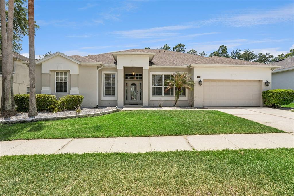 A single-story suburban house with a beige stucco exterior, a two-car garage, and a lawn — 259 NORTHAMPTON DRIVE, DAVENPORT, FL