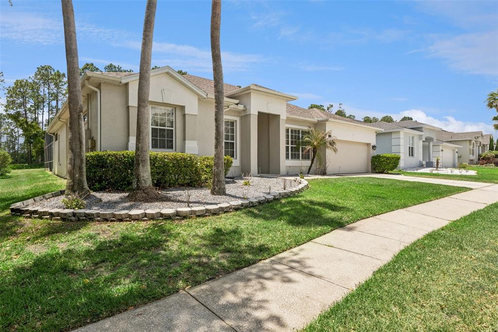 A single-story suburban house with a beige stucco exterior, a garage, and palm trees — 259 NORTHAMPTON DRIVE, DAVENPORT, FL