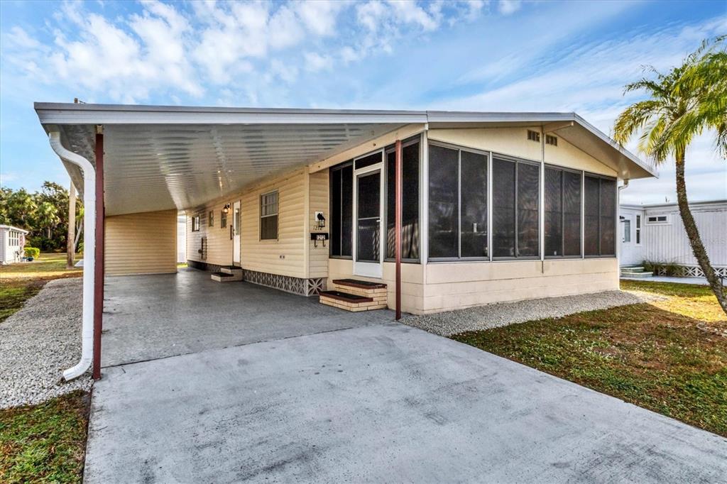 A single-story manufactured home with a carport, screened-in porch, and light-colored siding — 1212 45TH AVENUE E, ELLENTON, FL