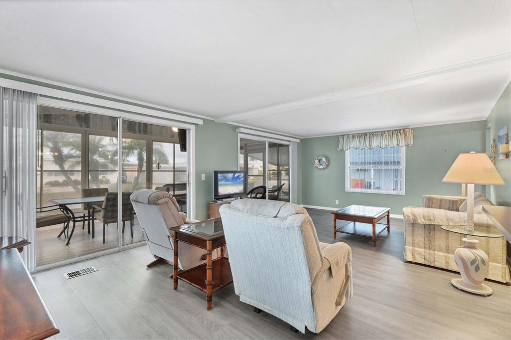 A living room with light gray flooring, sage green walls, and sliding glass doors to a patio — 1212 45TH AVENUE E, ELLENTON, FL