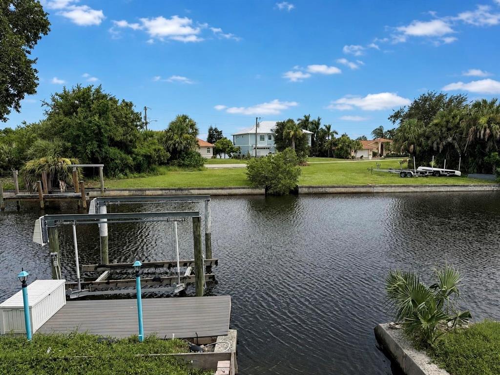 A boat lift sits in a canal in front of a grassy yard and houses — 155 DANFORTH DR, PUNTA GORDA, FL