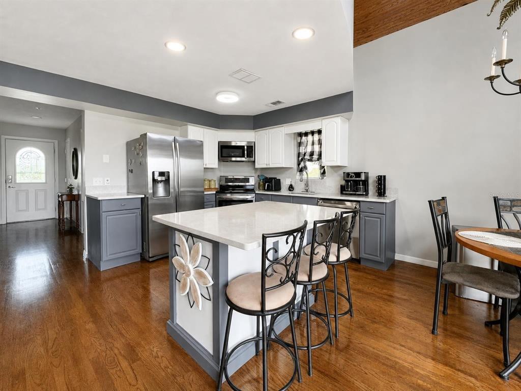 A kitchen with a central island, grey lower cabinets, white upper cabinets, and hardwood floors — 155 DANFORTH DR, PUNTA GORDA, FL