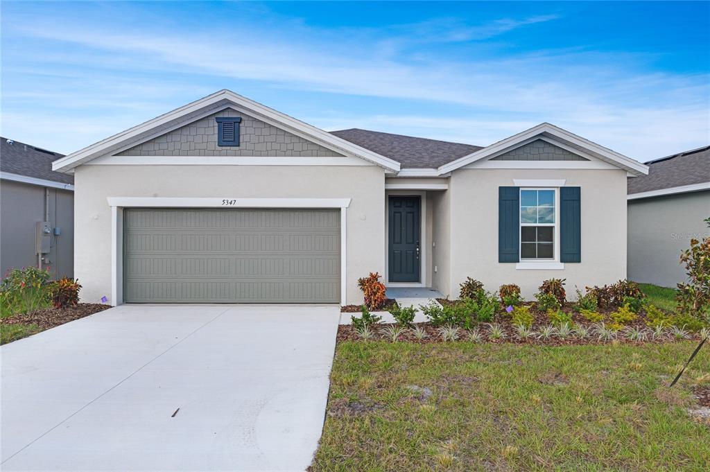 A single-story suburban house with a two-car garage, light stucco siding, and blue shutters — 5347 MICKEY AVENUE, WINTER HAVEN, FL
