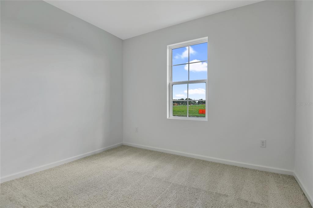 An empty bedroom with light gray walls, beige carpet, and a single window — 5347 MICKEY AVENUE, WINTER HAVEN, FL