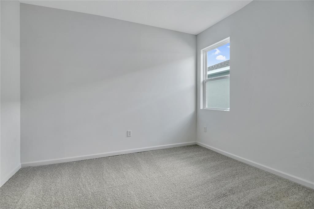 An empty room with light gray walls, gray carpet, and a single window — 5347 MICKEY AVENUE, WINTER HAVEN, FL