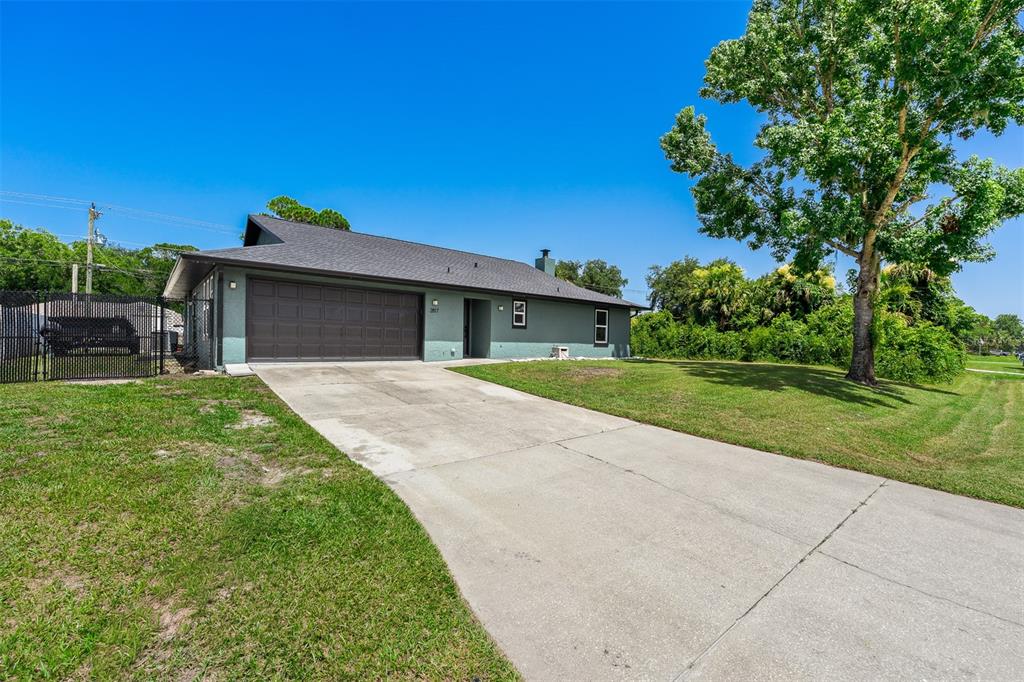 A single-story house with a green exterior, a dark roof, and a concrete driveway — 2817 YULE TREE DRIVE, EDGEWATER, FL