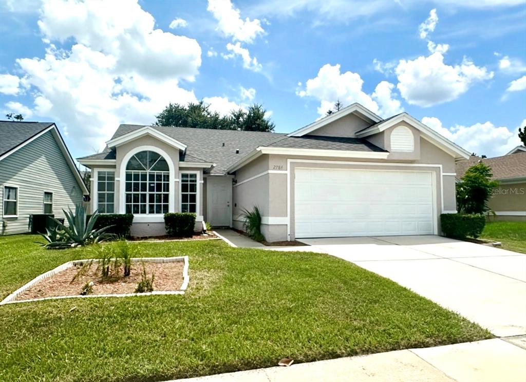 A single-story house with a beige exterior, a white garage door, and a front lawn — 2784 FALLING TREE CIRCLE, ORLANDO, FL