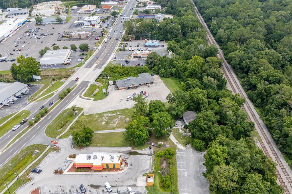 An aerial view shows commercial buildings, a parking lot, a road, and adjacent railroad tracks — S WALNUT STREET, STARKE, FL