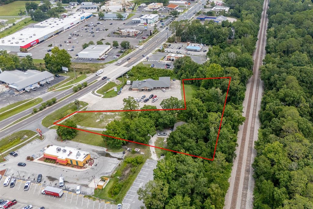 An aerial view shows a wooded lot outlined in red next to a commercial area — S WALNUT STREET, STARKE, FL