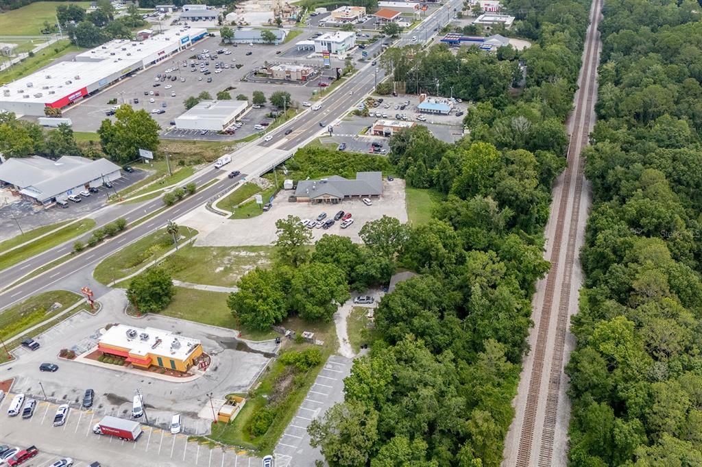 An aerial view shows a commercial area with parking lots, a road, and adjacent railroad tracks — S WALNUT STREET, STARKE, FL