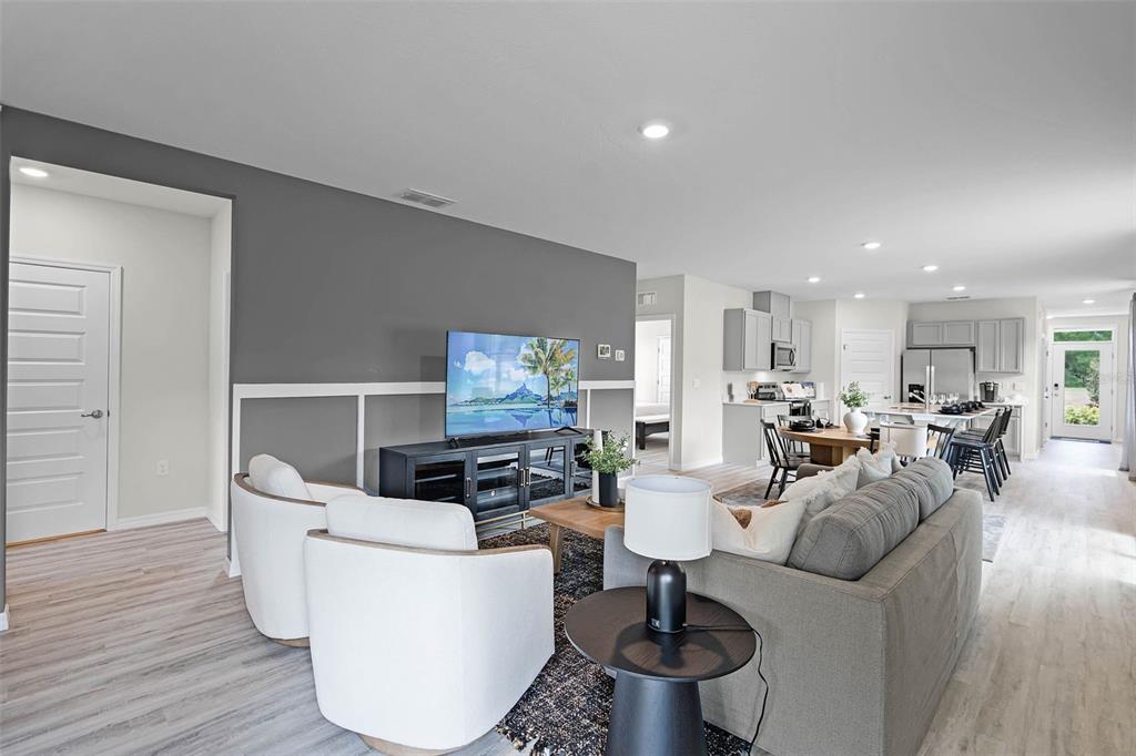 An open-concept living room features a gray accent wall, white wainscoting, and a modern kitchen — 1510 LAS PALMAS STREET, LAKELAND, FL