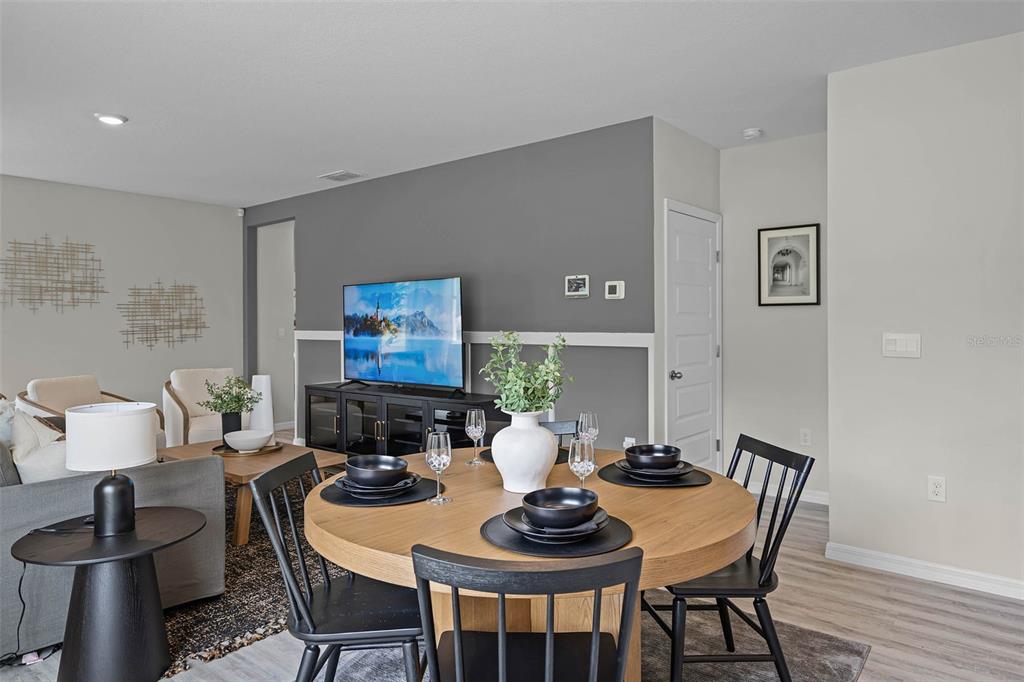 A dining area with a round wooden table and black chairs sits before a living room — 1510 LAS PALMAS STREET, LAKELAND, FL