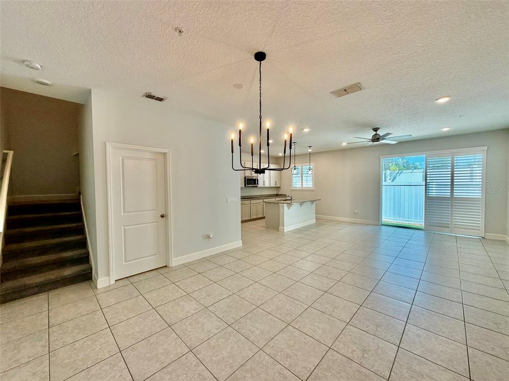 An open-concept living area features tile flooring, a kitchen island, and a dining chandelier — 960 GRAND WILDMERE COVE, LONGWOOD, FL