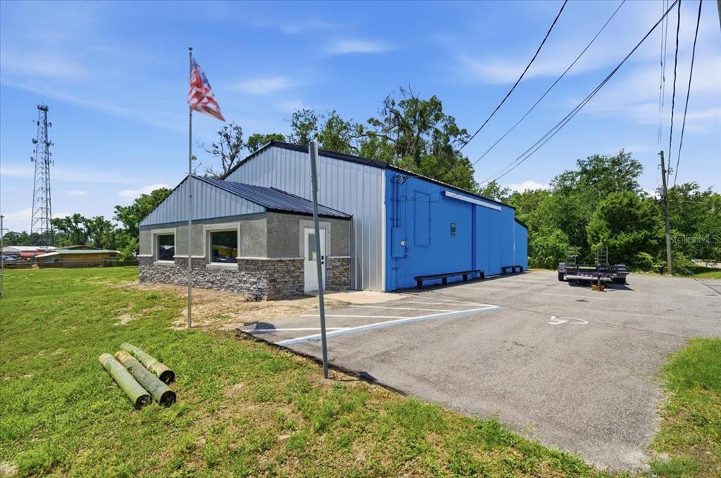 A blue metal building with a stone-accented facade stands next to a paved parking lot — 490 SMITH STREET, BROOKSVILLE, FL
