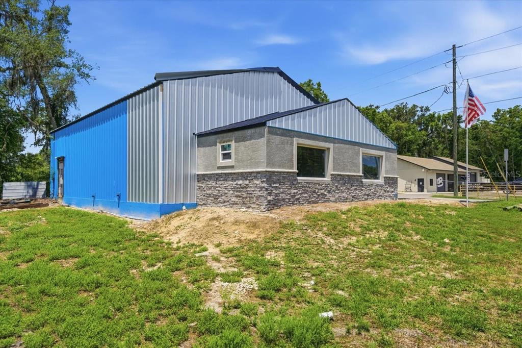 A metal-sided building with a stone-accented facade and a small American flag on a pole — 490 SMITH STREET, BROOKSVILLE, FL