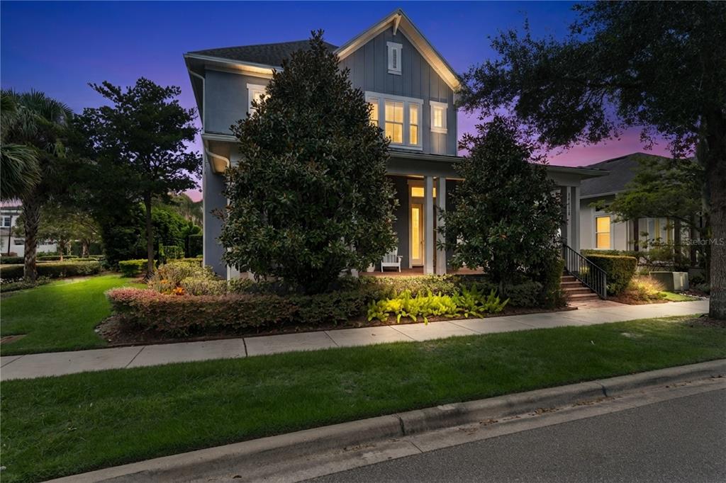 A two-story blue house with a front porch and landscaping at dusk — 13117 LESSING AVENUE, ORLANDO, FL