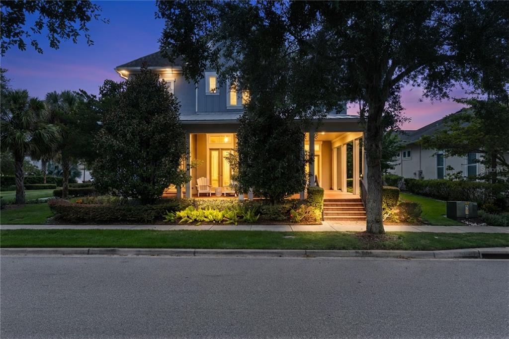 A two-story house with a covered front porch and landscaping at dusk — 13117 LESSING AVENUE, ORLANDO, FL