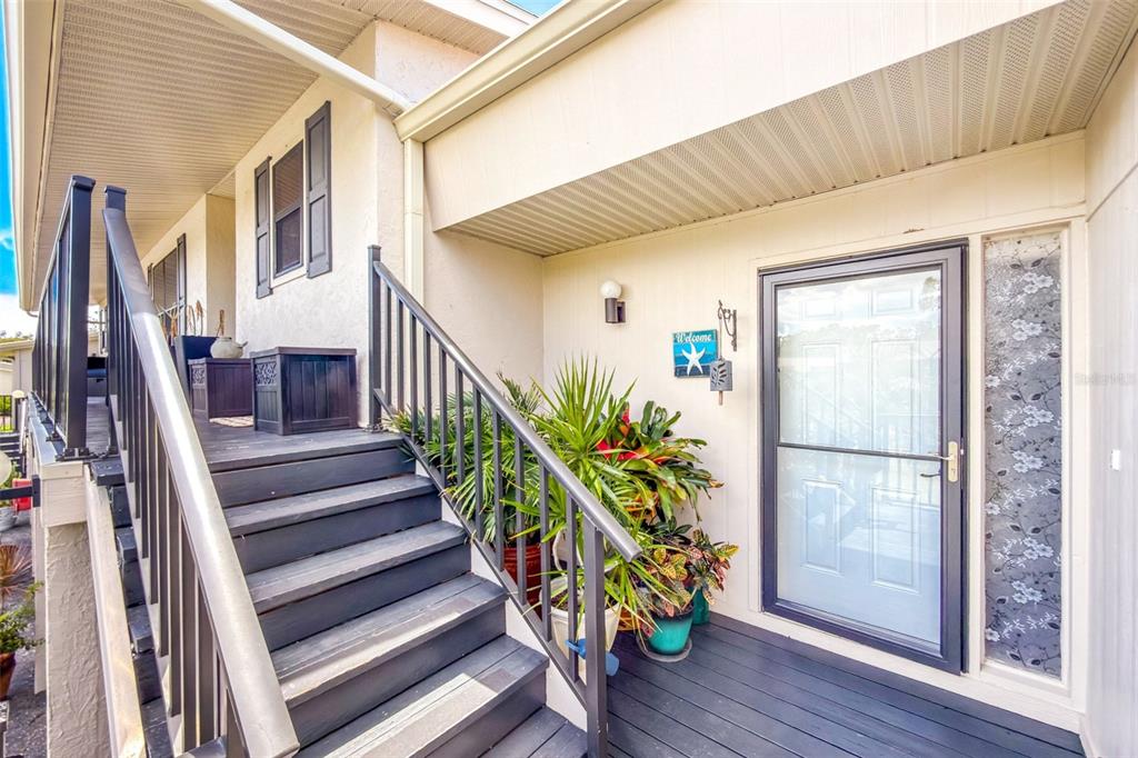 An exterior view of a raised wooden staircase leading to a front door with sidelight — 4260 PLACIDA ROAD UNIT 17D, ENGLEWOOD, FL