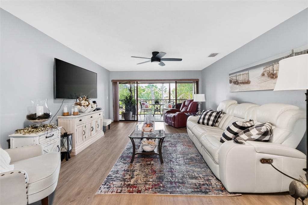 A living room features a white sofa, a glass coffee table, and a balcony view — 4260 PLACIDA ROAD UNIT 17D, ENGLEWOOD, FL