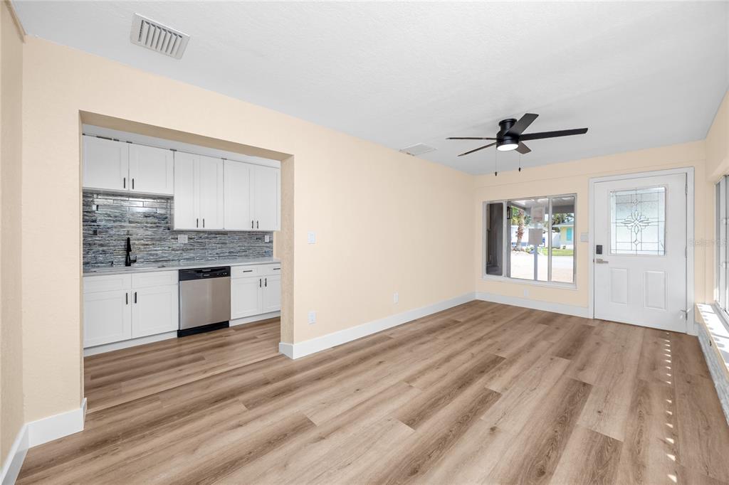 A room with light-colored walls, wood-look flooring, a ceiling fan, and an adjacent kitchenette — 504 79TH AVENUE, ST PETE BEACH, FL