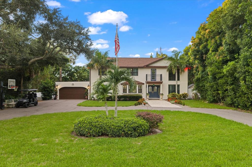 A two-story house with a brown roof, arched garage, and a flag pole in front — 3005 SUNSET DRIVE, BELLEAIR BLUFFS, FL