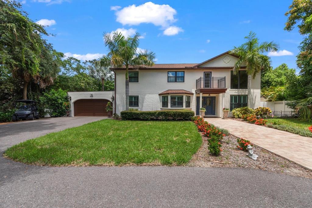 A two-story house with a white stucco exterior, a brown garage, and a paved driveway — 3005 SUNSET DRIVE, BELLEAIR BLUFFS, FL