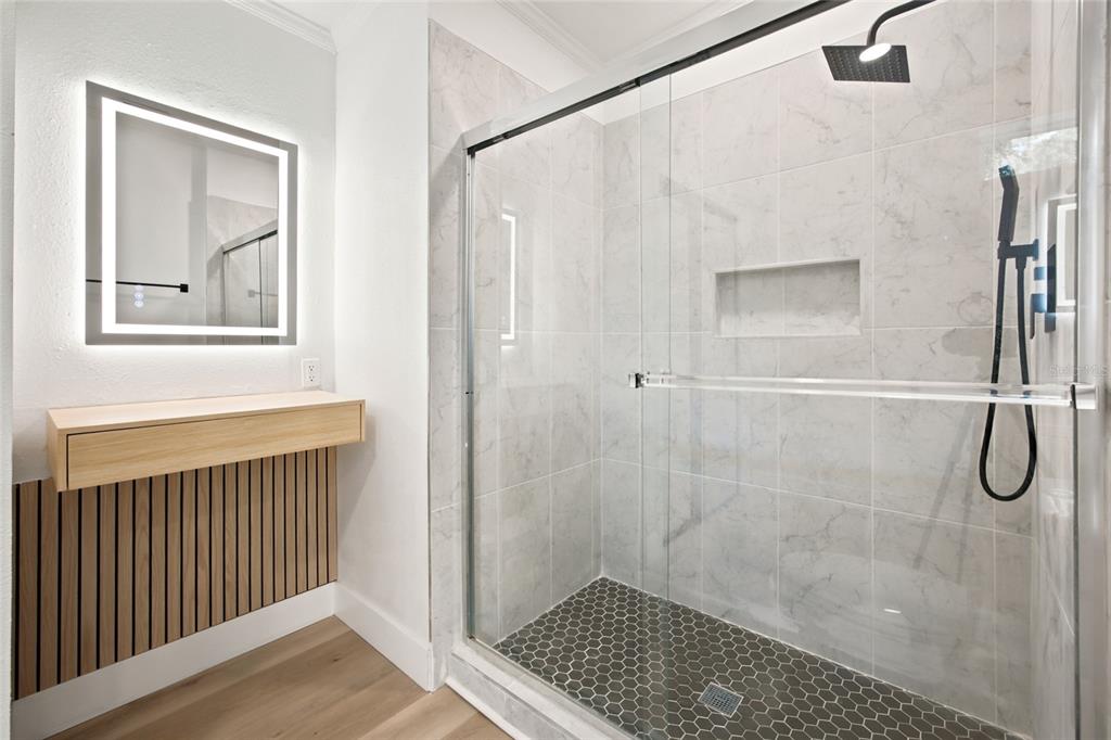 A bathroom features a glass-enclosed shower with marble-look tiles and a floating wood vanity — 2625 SE 140TH PLACE, SUMMERFIELD, FL