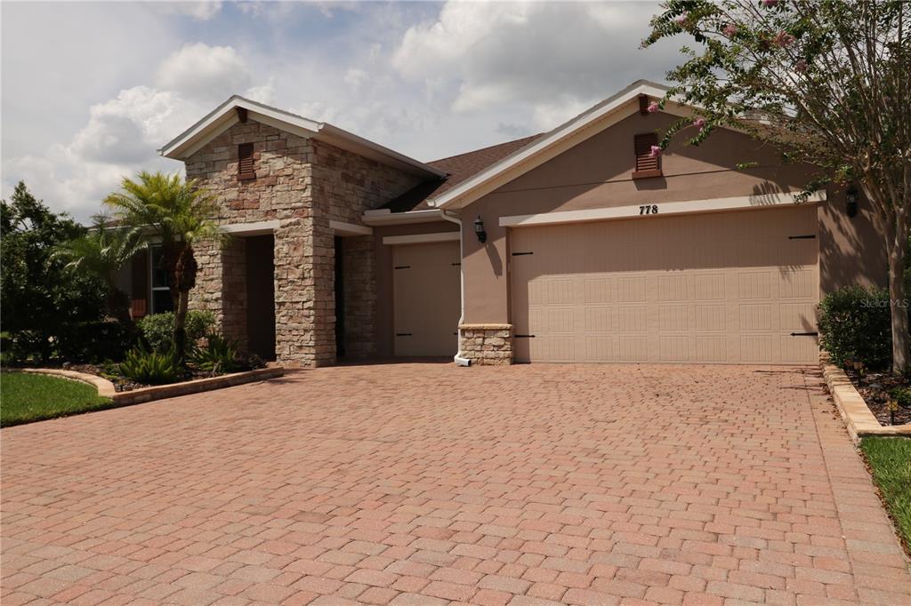 A single-story house with a stone facade, a brick paver driveway, and a two-car garage — 778 IRVINE RANCH ROAD, POINCIANA, FL