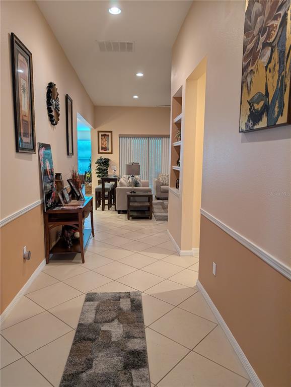 A tiled hallway leads into a living room with a console table and wall art — 778 IRVINE RANCH ROAD, POINCIANA, FL