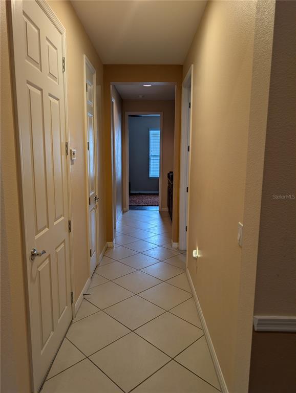 A hallway with beige walls and light-colored diagonal floor tiles leads to another room — 778 IRVINE RANCH ROAD, POINCIANA, FL