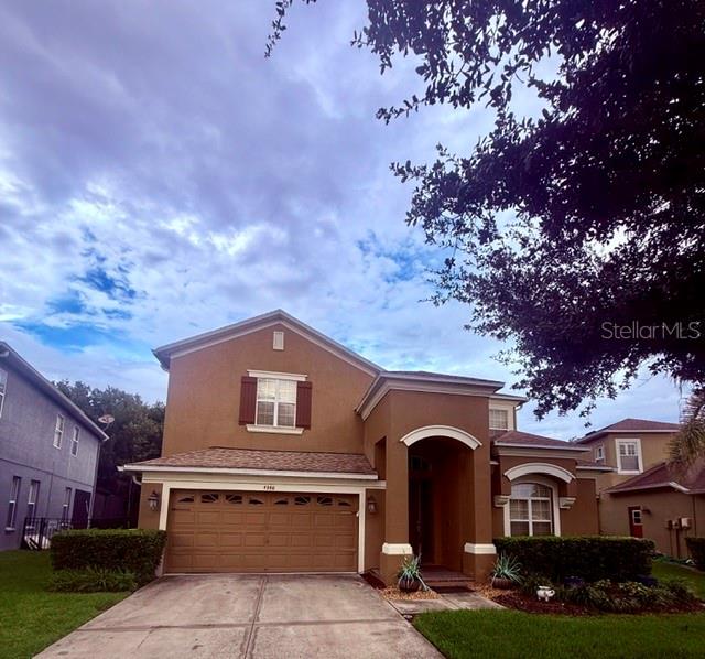 A two-story tan house with a two-car garage and a large tree in the yard — 4346 WATERVILLE AVENUE, WESLEY CHAPEL, FL