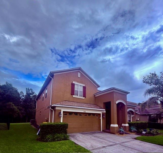 A two-story house with a tan stucco exterior, a two-car garage, and a cloudy sky — 4346 WATERVILLE AVENUE, WESLEY CHAPEL, FL