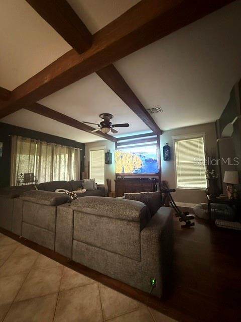 A living room features a large sectional sofa, exposed wooden ceiling beams, and a television — 4346 WATERVILLE AVENUE, WESLEY CHAPEL, FL