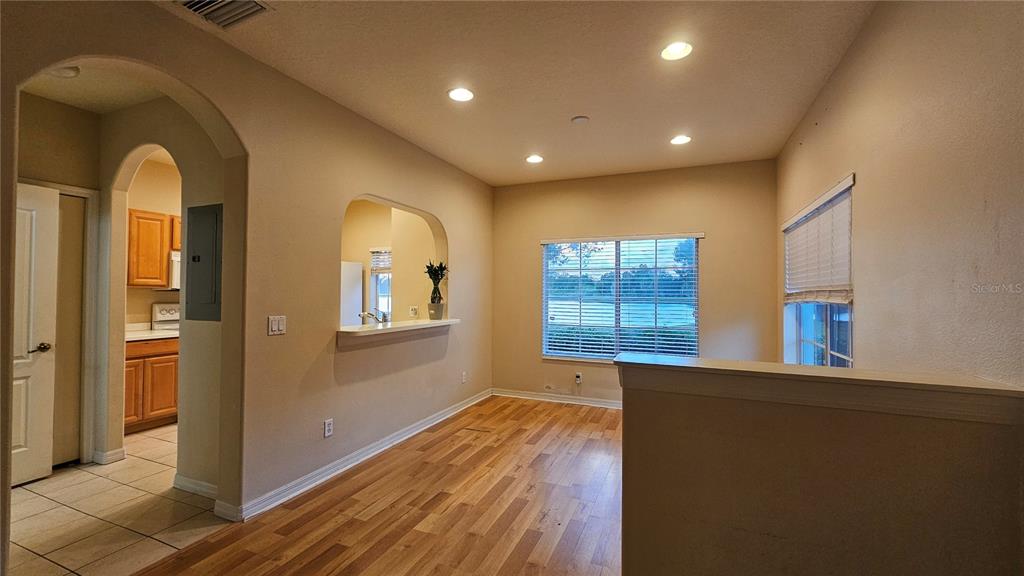 A dining room with wood-look flooring, recessed lighting, and a view of a lake — 220 CAPE HARBOUR LOOP UNIT 108, BRADENTON, FL
