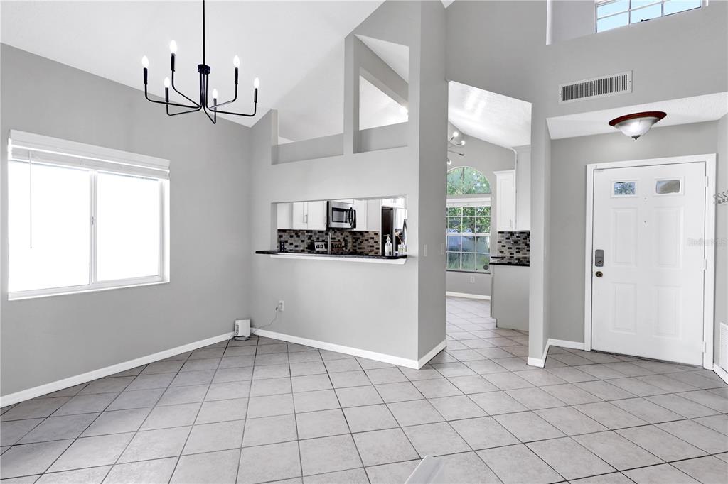 A dining area with gray walls, tile flooring, a chandelier, and a kitchen pass-through window — 789 HEATHER GLEN CIRCLE, LAKE MARY, FL