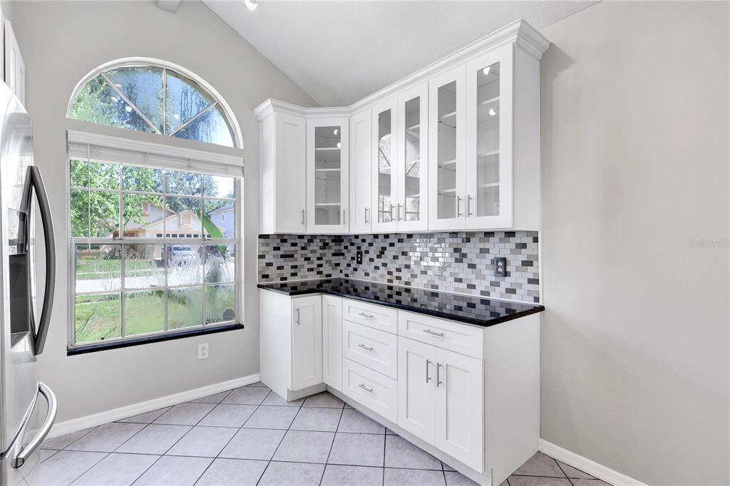 A kitchen corner features white cabinets, a black countertop, and a gray mosaic tile backsplash — 789 HEATHER GLEN CIRCLE, LAKE MARY, FL