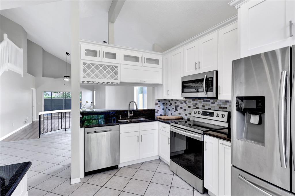A kitchen with white cabinets, stainless steel appliances, and a dark granite countertop — 789 HEATHER GLEN CIRCLE, LAKE MARY, FL