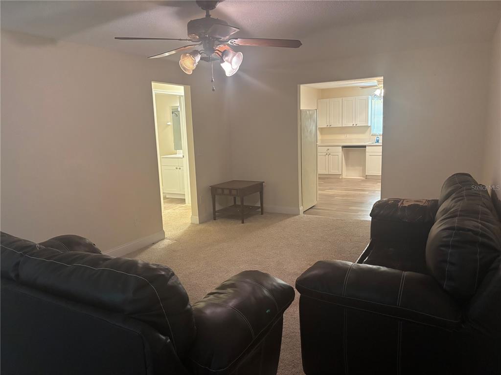 A living room with carpeted floors, two dark leather sofas, and views into a kitchen — 7546 SONIA DRIVE, JACKSONVILLE, FL