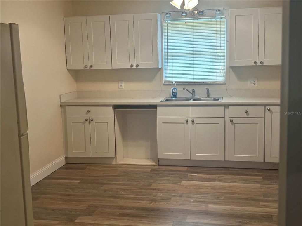 A kitchen features white cabinets, a double sink, and wood-look flooring — 7546 SONIA DRIVE, JACKSONVILLE, FL