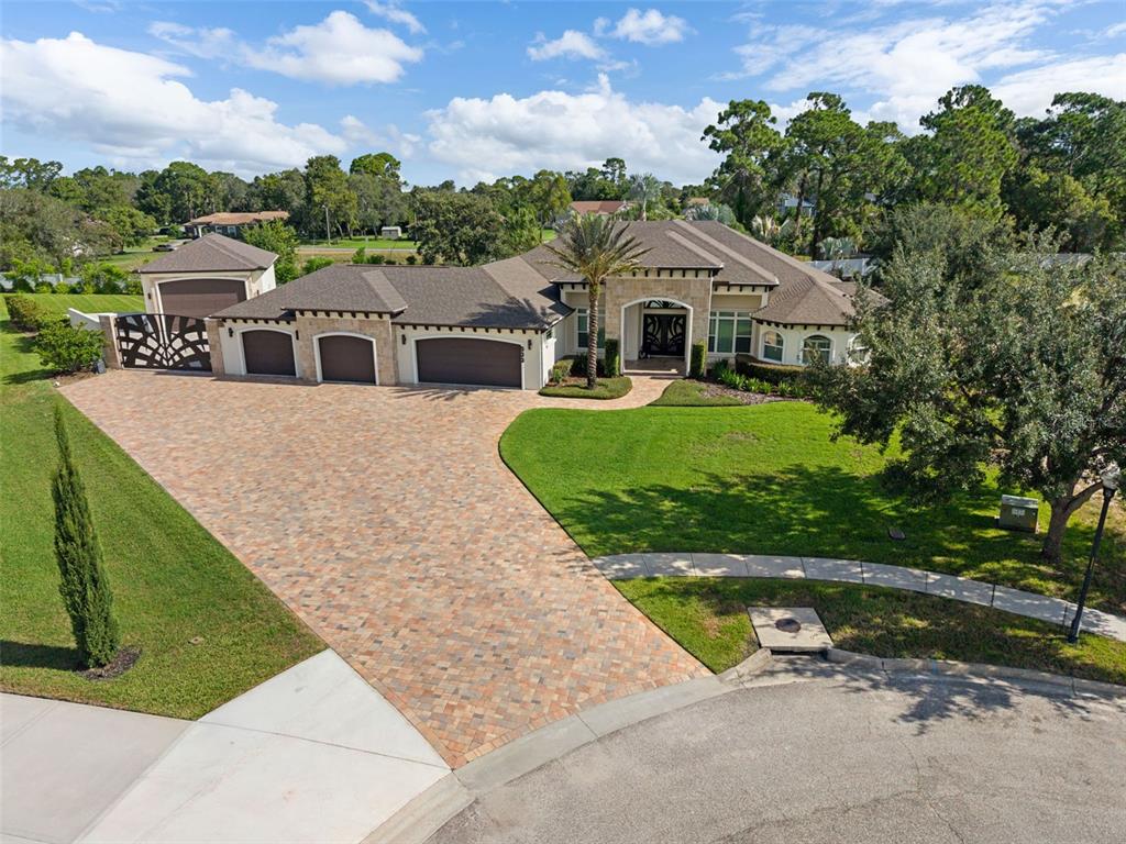 An aerial view of a single-story house with a large paver driveway and three-car garage — 533 STORYBOOK LANE, SPRING HILL, FL