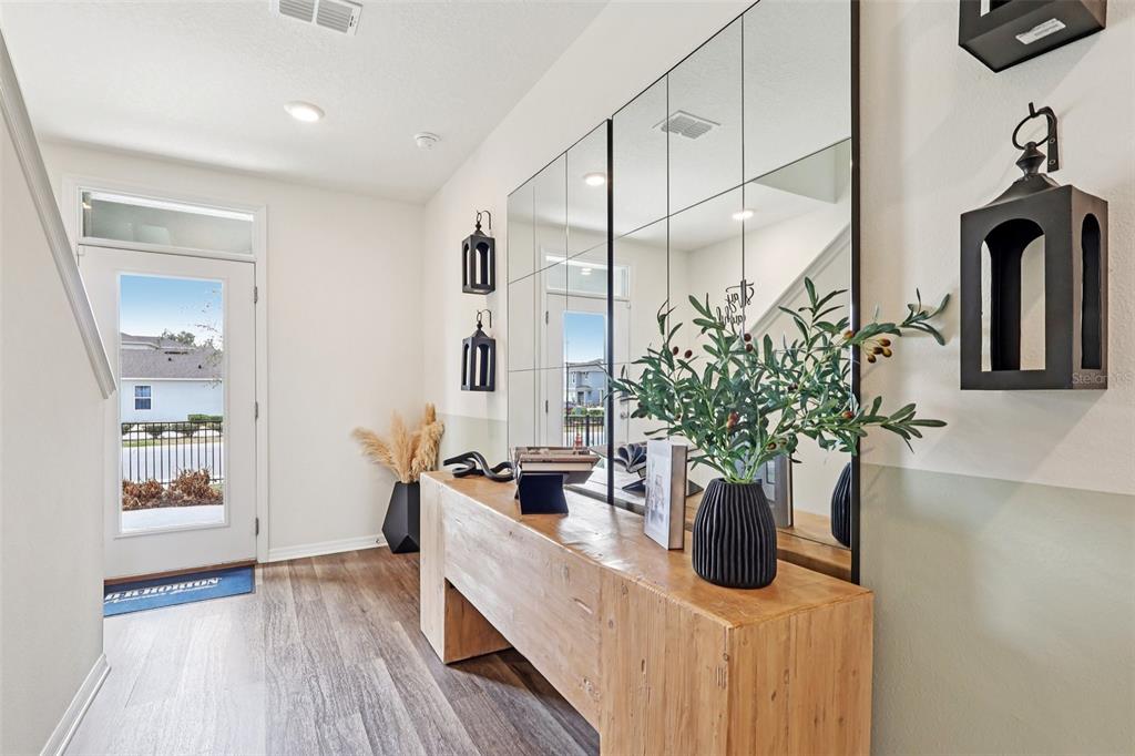 An entryway features a wooden console table, large wall mirrors, and a white front door — 4209 BIXBY BRIDGE PLACE, DAVENPORT, FL